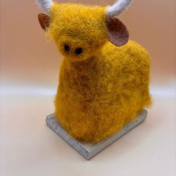 Large highland cow on wooden base
