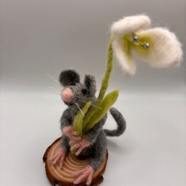 Mouse holding a snowdrop on wood slice