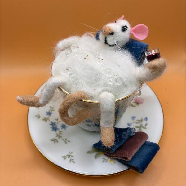Mouse relaxing in a teacup with a glass of wine