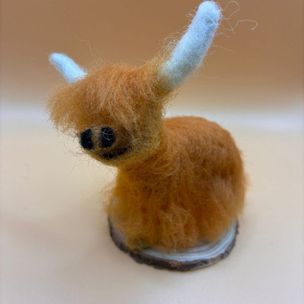 Small highland cow on wood slice